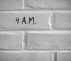 PHOTO OF 4 A.M. WRITTEN ON WHITE PLAIN BRICK WALL