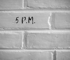 PHOTO OF 5 P.M. WRITTEN ON WHITE PLAIN BRICK WALL