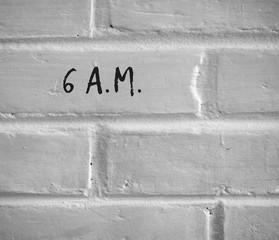 PHOTO OF 6 A.M. WRITTEN ON WHITE PLAIN BRICK WALL