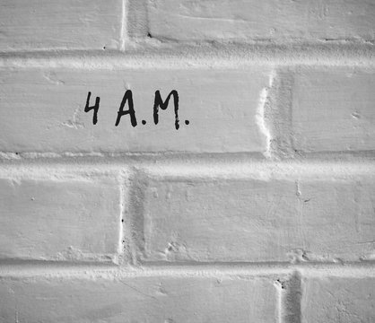 PHOTO OF 4 A.M. WRITTEN ON WHITE PLAIN BRICK WALL
