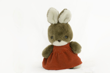 Rabbit doll wearing red dress standing on a white background.