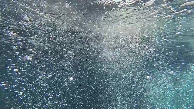 Underwater slow motion shot of many bubbles moving up from divers