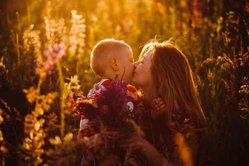 Mom sits with her son on the field in the lights of evening sun