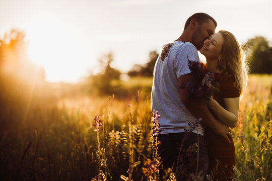 Cheerful couple hugs each other tender standing on the green field