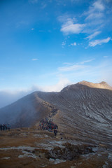 Hundreds of tourists on mountains Kawah Ijen Volcano crater going to see Sulfuric acidic big lake a famous in Indonesia