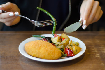 Vegetable stew and chicken cutlet female hands