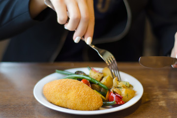 Vegetable stew and chicken cutlet female hands