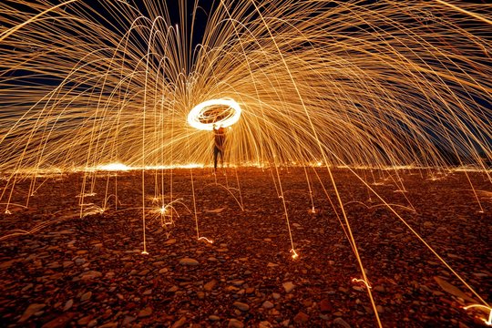 Man spinning illuminated steel wool at night, Italy
