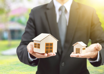 businessman hold big and small houses on hand