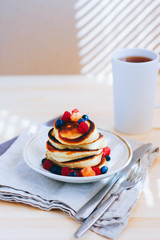 Breakfast, lush pancakes with fresh berries, raspberries and blueberries and a cup of tea