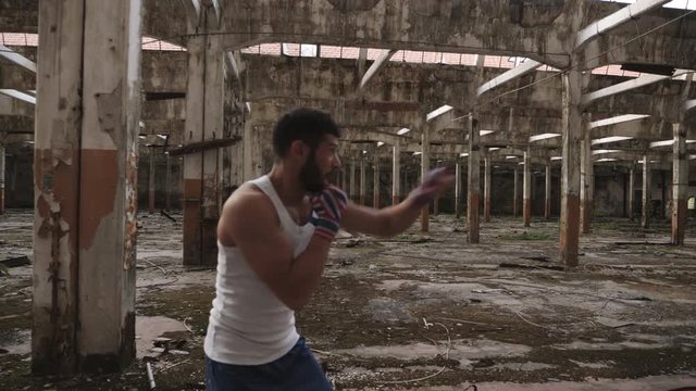 Young attractive male boxer doing shadow boxing exercise in an old abandoned building.