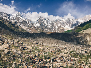 Fototapeta na wymiar Glacier covered with rocks and Shkhara mountain on background, Svaneti region, Georgia