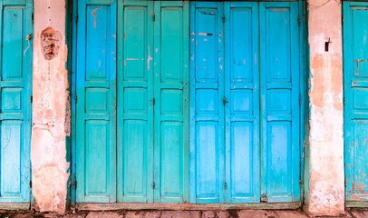 Old house with vintage wooden blue cyan door and gray cement wall. Vintage blue cyan doors concept use for background.