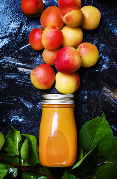 Fresh apricot juice in glass bottle, black background, top view