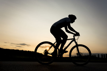 Silhouette of boy on the bike. Young cyclist is riding his bike during susnet. 