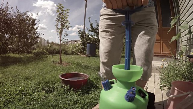 The gardener presses the apparatus for spraying plants with pesticides