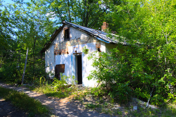 Destroyed houses in which people lived in a dead radioactive zone. Consequences of the Chernobyl nuclear disaster and vandalism, August 2017.