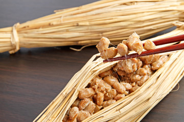Natto fermented soy beans wrapped in rice straw on wood background