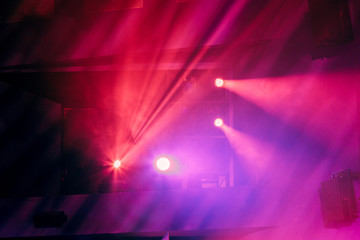 Verlichtingsapparatuur op het podium van het theater tijdens de voorstelling. De lichtstralen van de schijnwerper door de rook. Rode en paarse lichtstralen.
