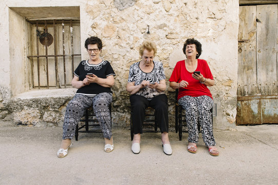 Three women of age advanced with smartphone