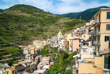 Fototapeta premium The small village of Manarola, with its colorful houses hanging to the hills alongside the main street, is one of the five town of the Cinque Terre in Liguria.