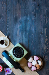 Old vintage telephone, with biscotti, caffè, donuts on a wooden background, free space for text