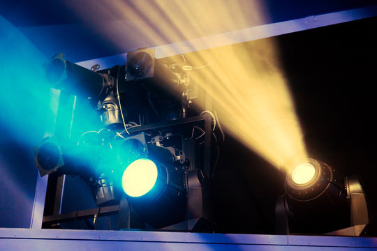 Lighting equipment on the stage of the theatre during the performance. The light rays from the spotlight through the smoke. Yellow and blue rays.