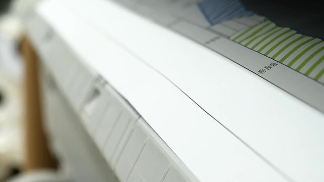 Wide format printer is printing color design draft outline sketch drawing in the printing house. Design office supply equipment.