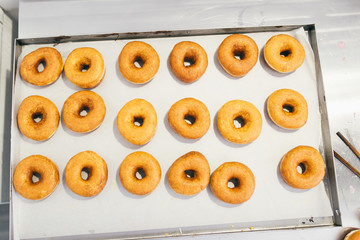 Fried donuts on baking sheet ready for decorating.