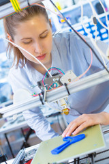 A female student or laboratory assistant in the automation laboratory is debugging the work of the 3d printer. 3d printer is a device for modeling 3D objects