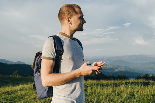 Closeup of a man's hand is holding mobile phone  against mountains, copy space