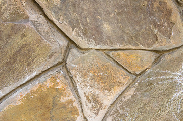 A wall of stones sprinkled to each other, separated by strips of cement.