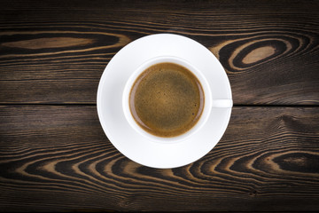 Overhead view of a freshly brewed mug of espresso coffee on rustic wooden background with woodgrain texture. Coffee break style, concept