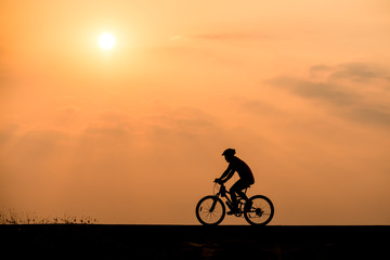 Naklejka na ściany i meble Silhouette of cyclist on sunset background