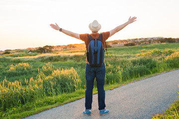 Man with arms raised, looking out over field