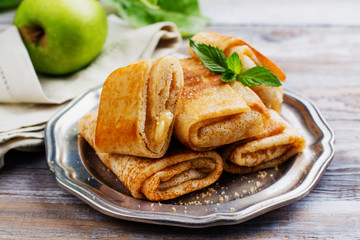 Crepes with apples, lemon and cinnamon on wooden table. Space for text