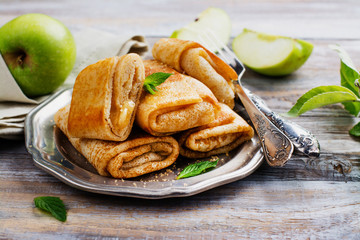 Crepes with apples, lemon and cinnamon on wooden table. Space for text