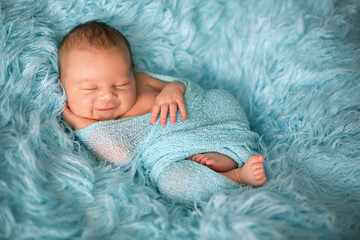 Happy smiling newborn baby in wrap, sleeping happily in cozy fur - obrazy, fototapety, plakaty
