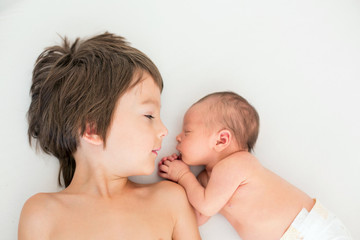 Beautiful boy, hugging with tenderness and care his newborn baby brother at home © Tomsickova