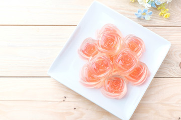 Jelly in rose shape in plate on wooden background