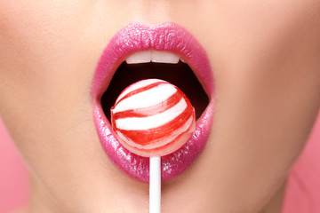 Lips of beautiful young woman with lollipop, closeup