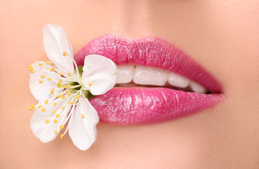 Lips of beautiful young woman with flower, closeup
