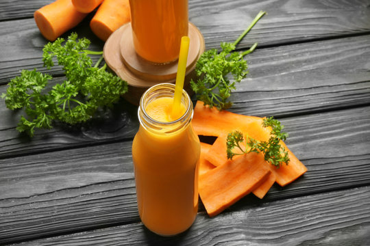 Bottle of fresh carrot smoothie on wooden table