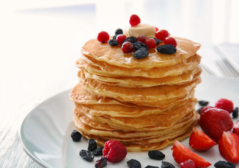 Plate with delicious pancakes on table