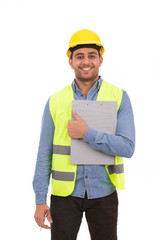 Happy young engineer smiling and holding a clipboard, guy wearing blue shirt and jeans with yellow vest and yellow helmet, isolated on white background