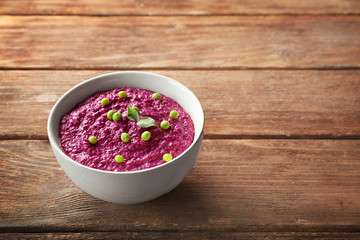 Bowl with delicious creamy beet hummus on table