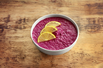 Bowl with delicious creamy beet hummus on wooden background