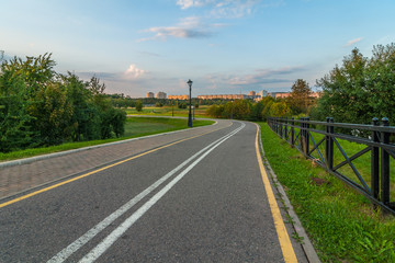 Fototapeta na wymiar deserted asphalt path in the city park in the early evening