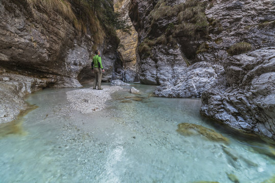 Dolomites, Belluno, Veneto, Italy. An hiker looking the turquoise water in Val Soffia, Mis valley