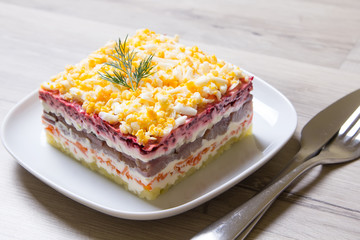 Herring under a Fur Coat. Traditional Russian multilayered salad from herring, beets, potatoes, carrots and eggs. Close-up, selective focus.